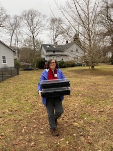 Gayle Anderson carrying a seed flat tray with seeds to overwintered